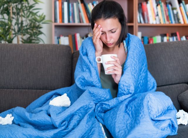 woman covered by a blanket on the sofa with high fever and flu