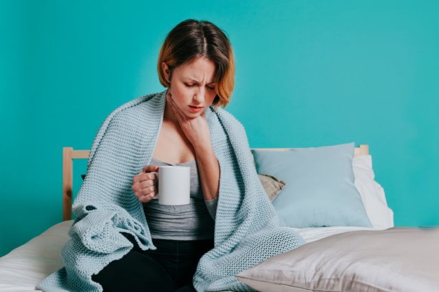 Woman sore throat with glass of water in her bed