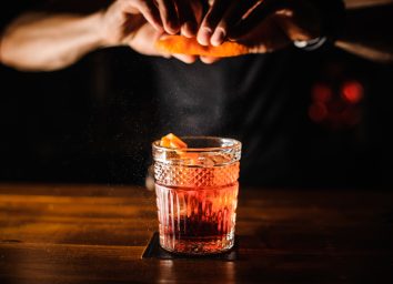 Bartender squeezing orange peel cocktail