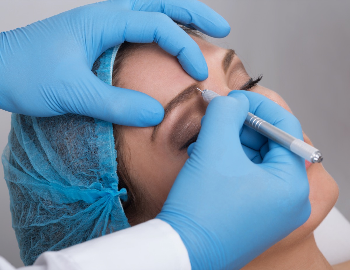 Close up of a cosmetologist applying a special permanent make up on a woman's eyebrows.