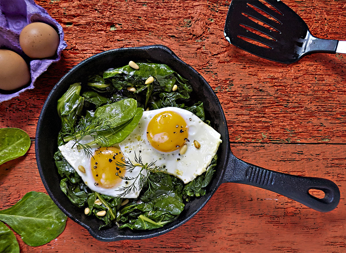 fried eggs with spinach in cast iron pan