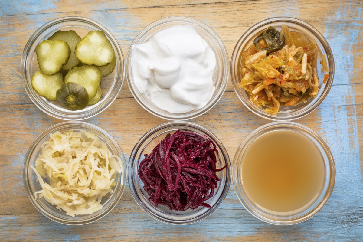 glass bowls against grunge wood: cucumber pickles, coconut milk yogurt, kimchi, sauerkraut, red beets, apple cider vinegar