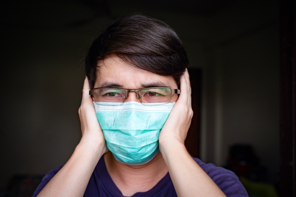man with eyeglasses wearing hygienic mask feeling headache