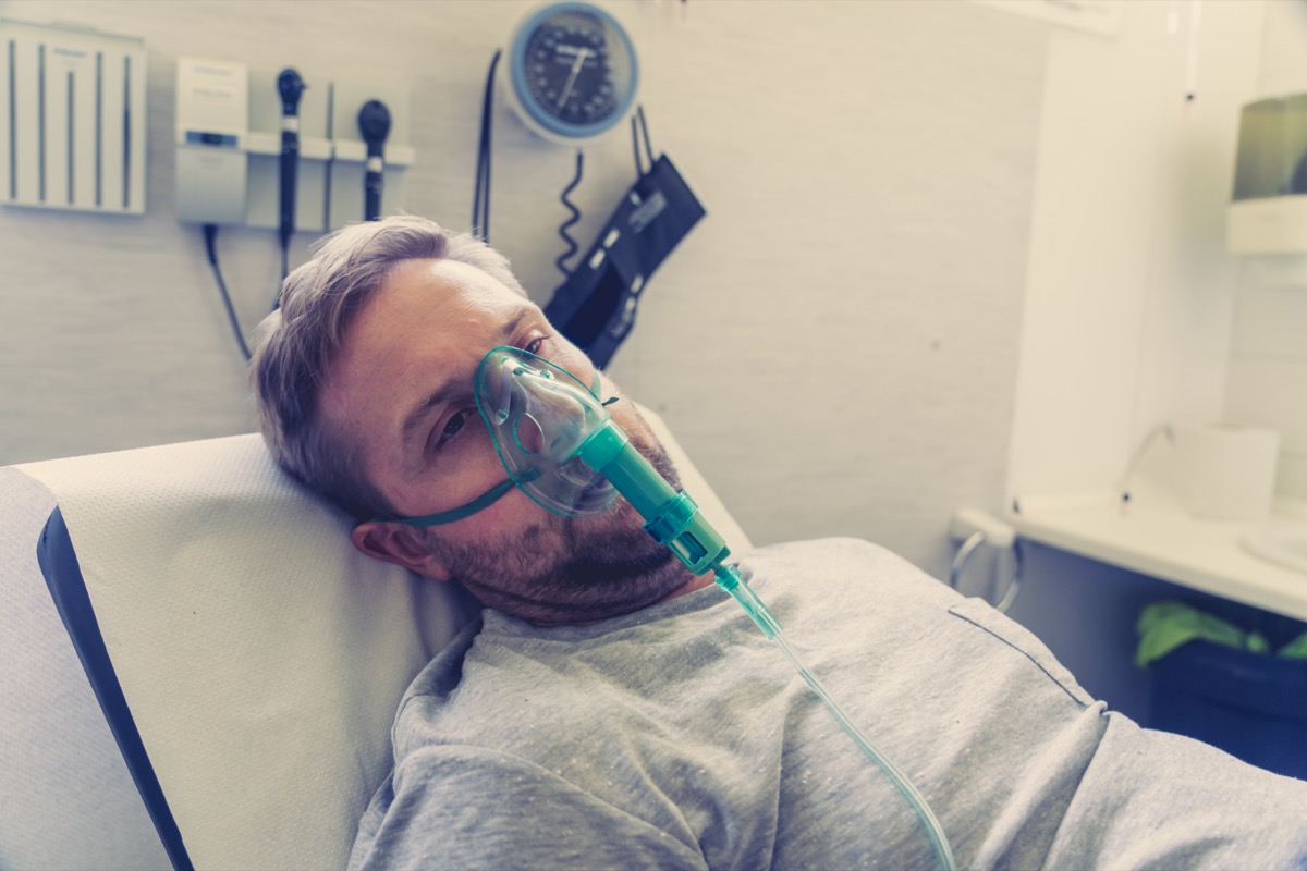 man with oxygen mask looking sad and worried at hospital bed in clinic bedroom