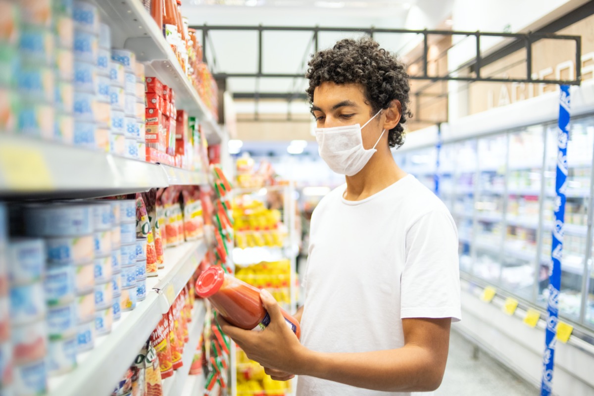22-year-old man with protective mask makes purchase in supermarket