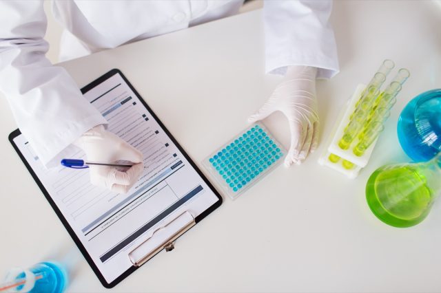 science, chemistry, biology, medicine and people concept - close up of scientist with test sample making research in clinical laboratory