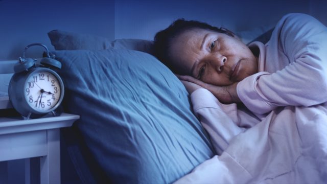 senior woman having sleep disorder, sitting in bed look sad