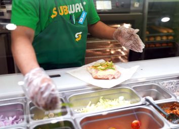 Subway sandwich artist making sub