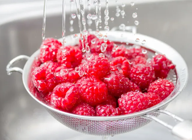 washing raspberries with water in strainer