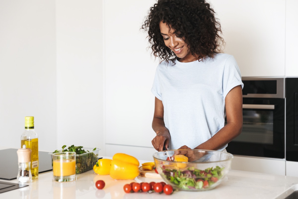 Portrait of a pretty afro american woman making a healthy salad at the kitchen