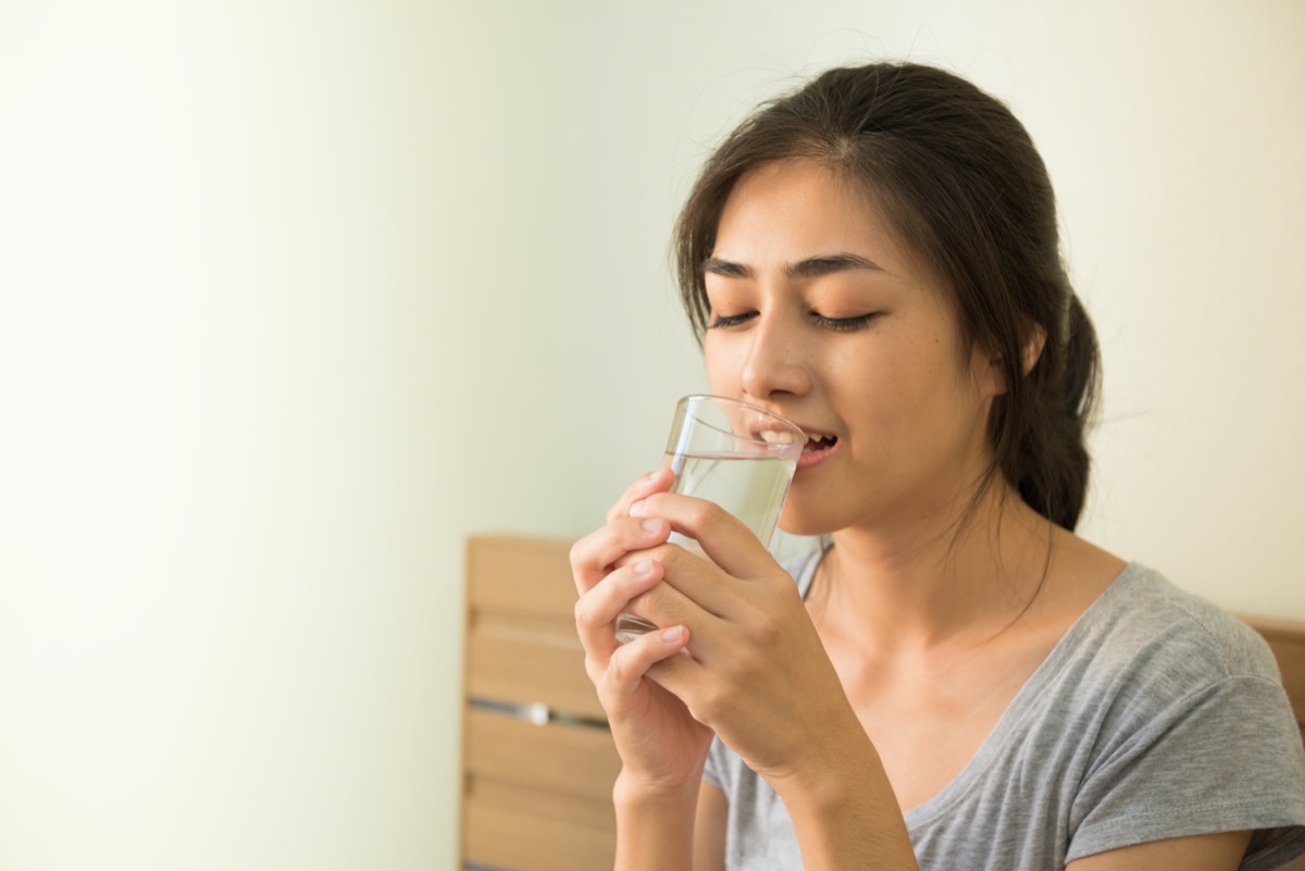 woman drinking glass of water in the morning