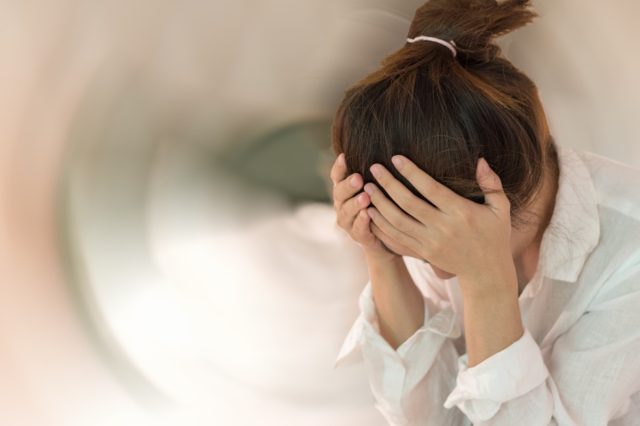 Woman hands on his head felling headache dizzy sense of spinning dizziness with motion