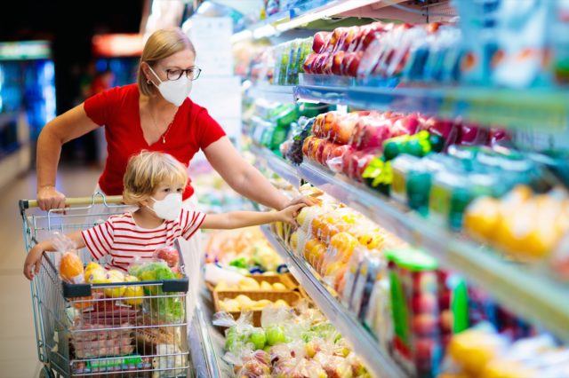 Mom and little boy buy fresh vegetable in grocery store. Family in shop.