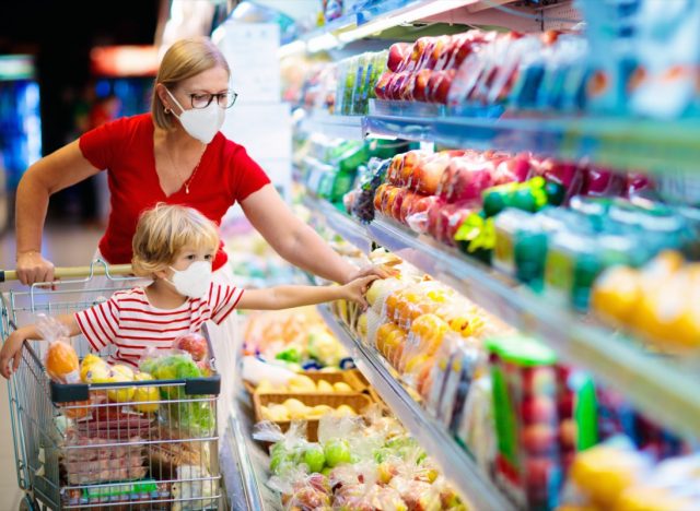 Mom and little boy buy fresh vegetable in grocery store. Family in shop.