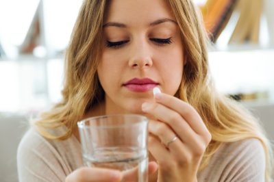 depressed young woman taking pills at home