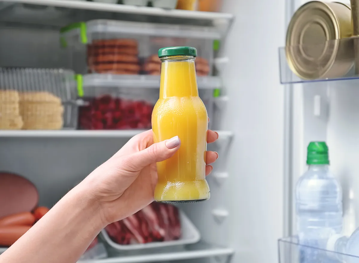 Unhealthy orange juice bottle held in front of fridge