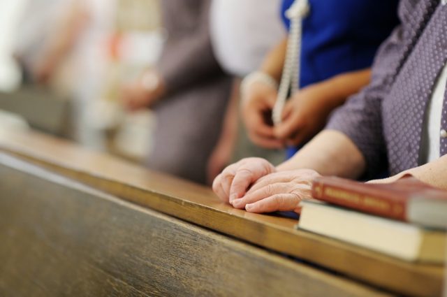 Hands of a senior woman while praying in a church