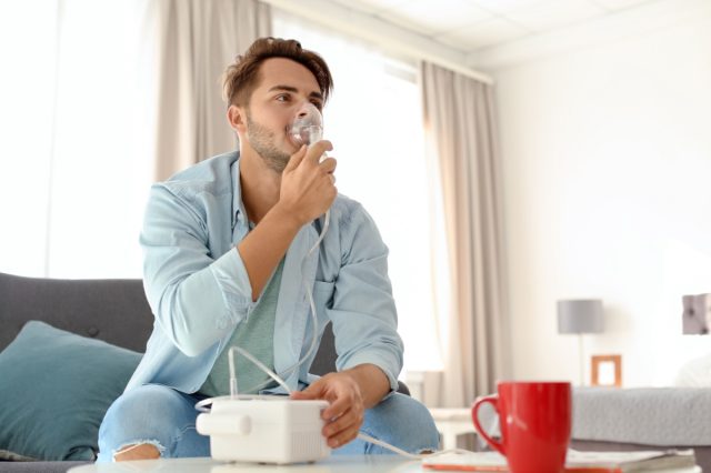 man using asthma machine at home.