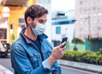 man with a beard chats on his phone and wears a face pollution mask to protect himself from coronavirus.