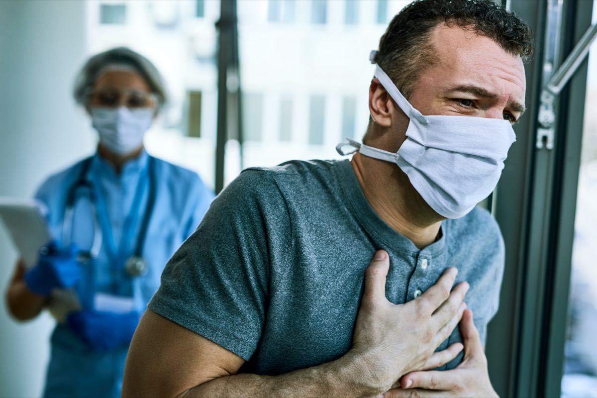 Male patient wearing face mask and feeling chest pain while being at the hospital during coronavirus epidemic