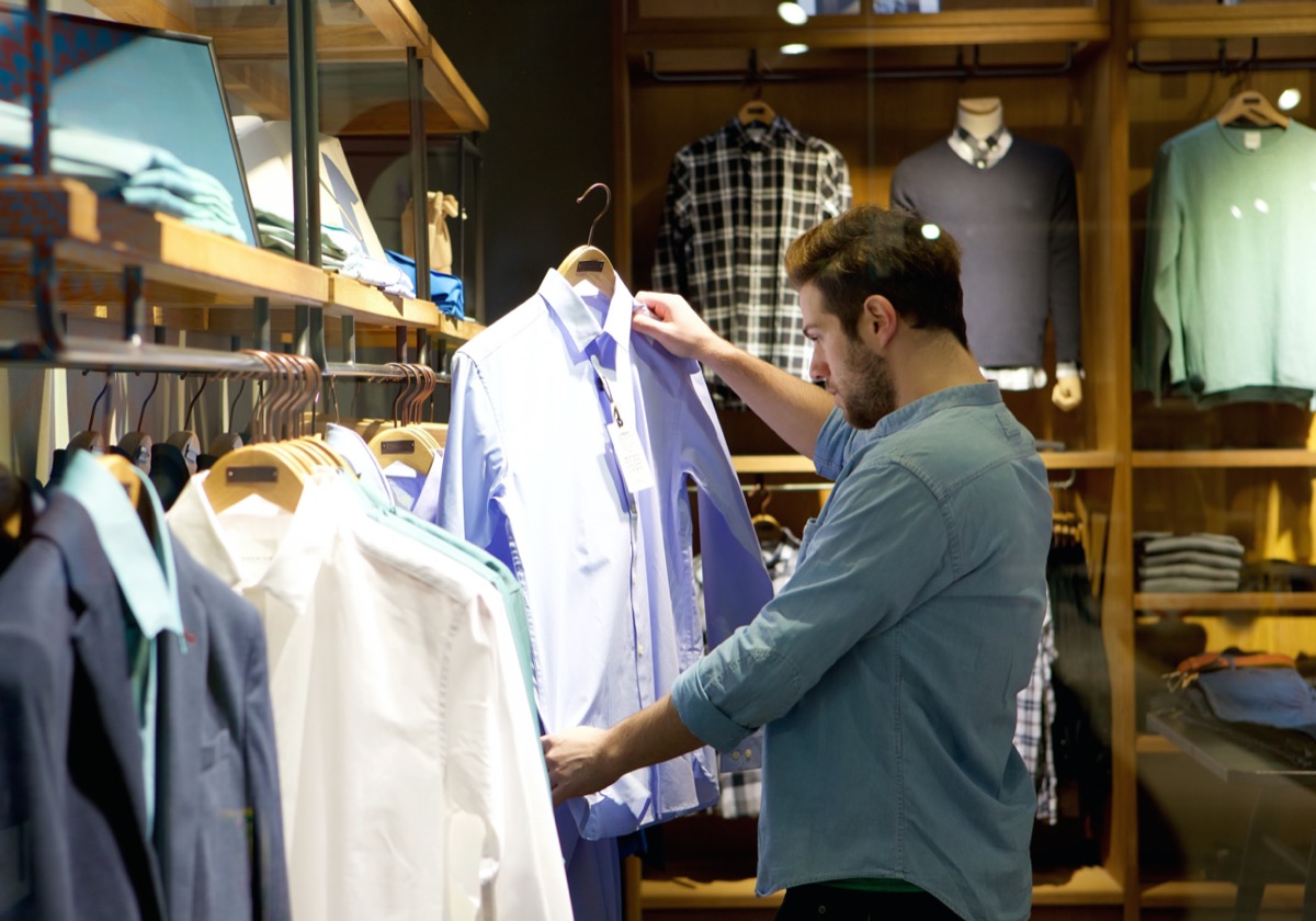 Portrait of a young man shopping for clothes at store