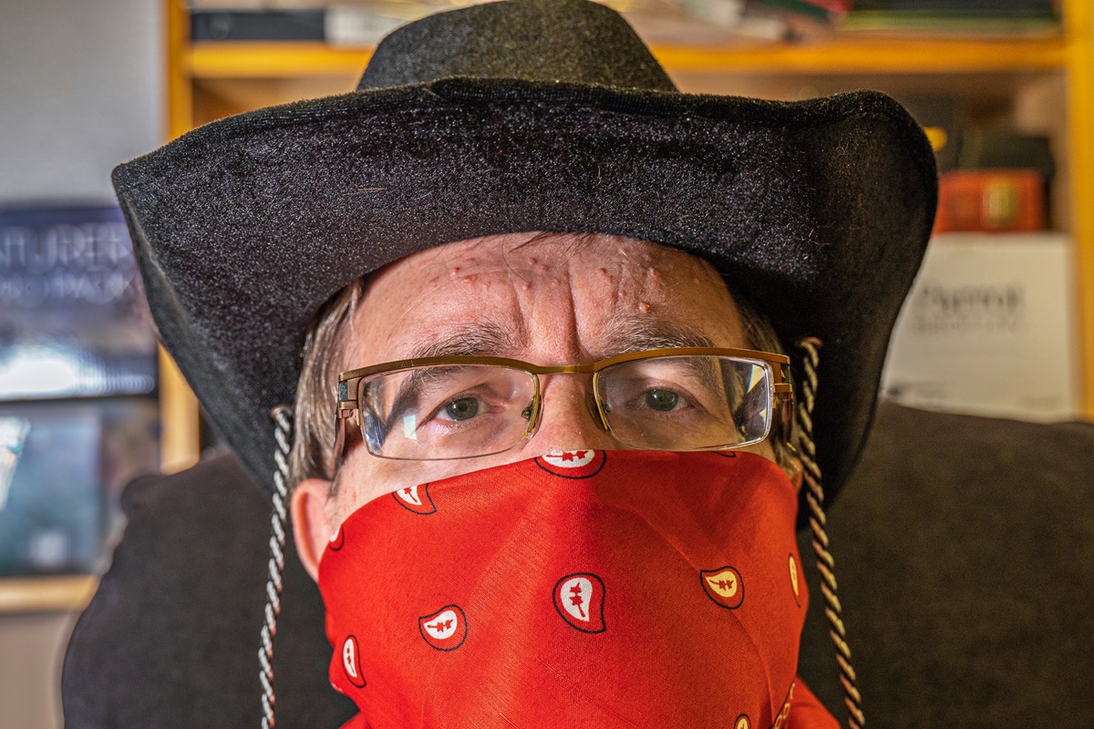Cowboy with kerchief mask and glasses practices social distancing during the Coronavirus crisis.