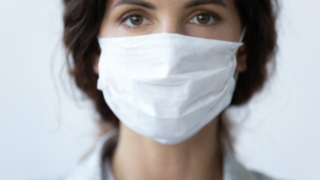 woman cover her face wearing facial medical blue mask