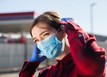 woman adjusting protective face mask,standing on petrol station parking lot