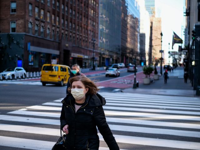 woman with mask walking in nearly empty new york street