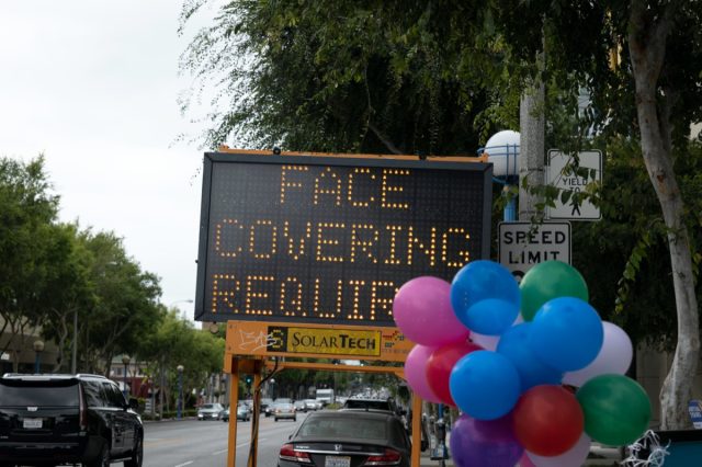 a road sign still reads Face Covering Required for coronavirus