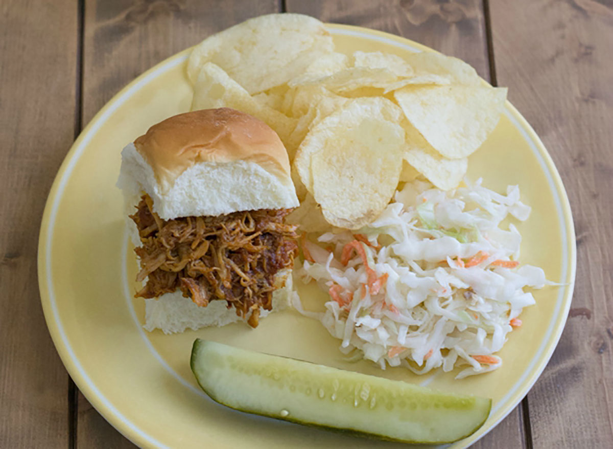 crock pot coca cola pulled chicken sliders on plate with pickle spear chips coleslaw