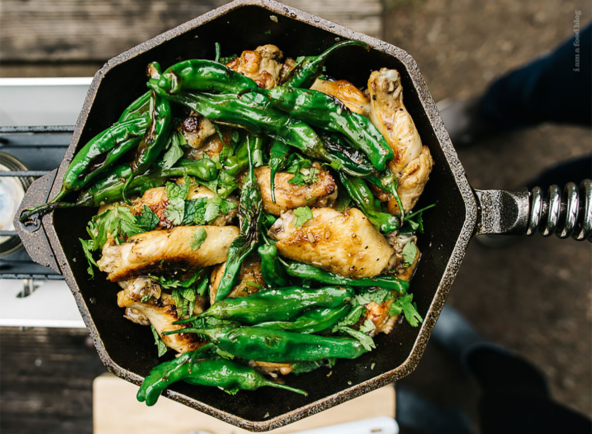 chicken wings made with fish sauce and whole shishito peppers in skillet