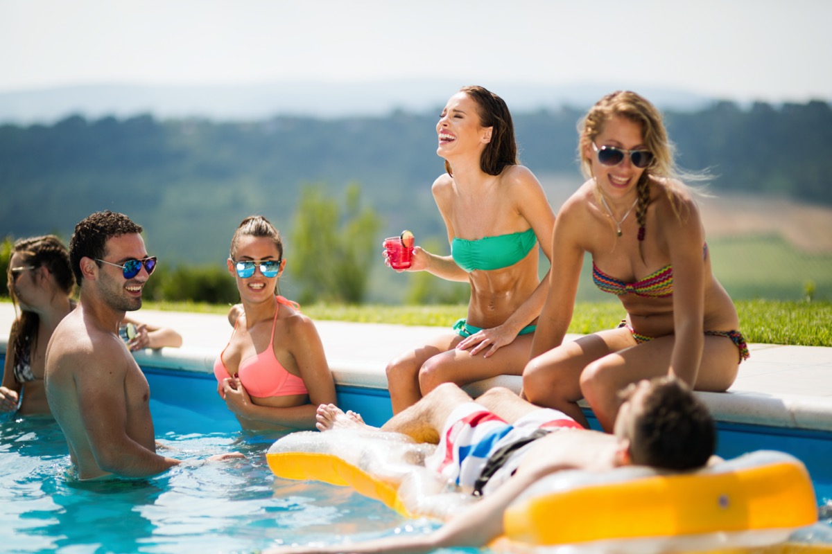 Group Of Friends Having Party In Pool Drinking Champagne