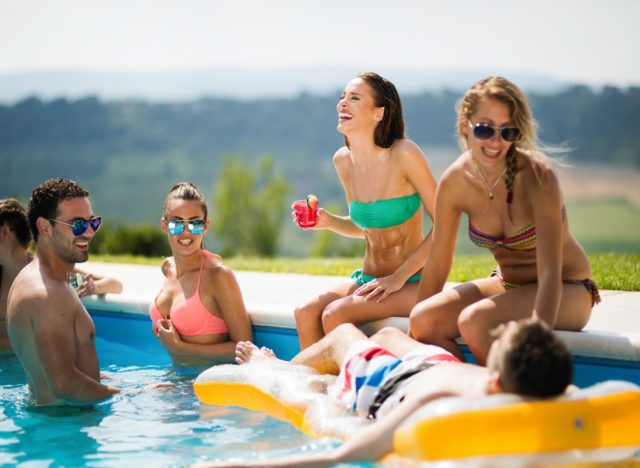 Group Of Friends Having Party In Pool Drinking Champagne