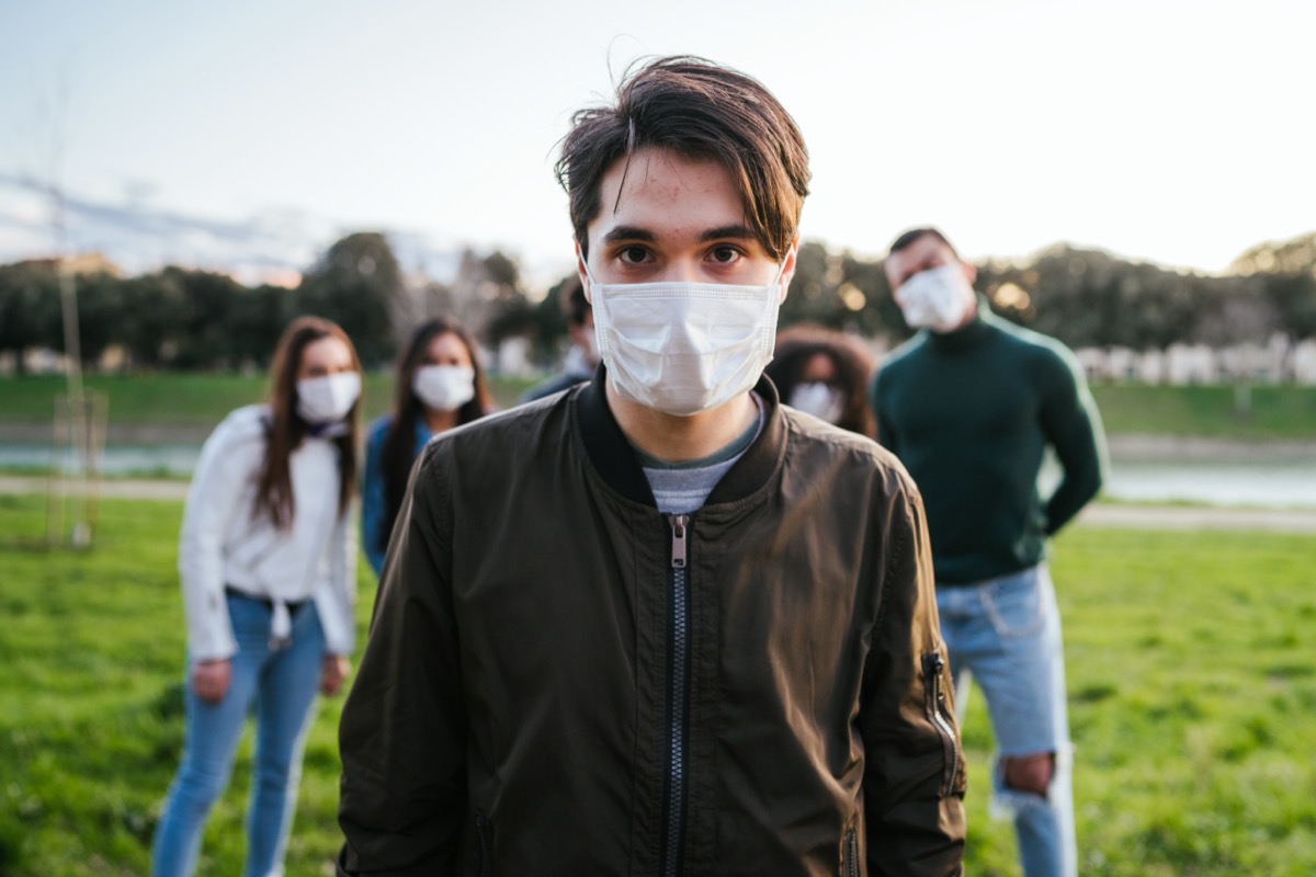 Group of teenagers friends at park wearing medical masks.