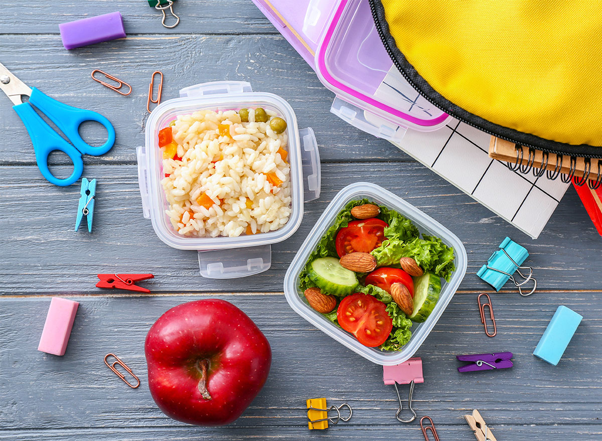 lunch boxes with kids school supplies and whole apple