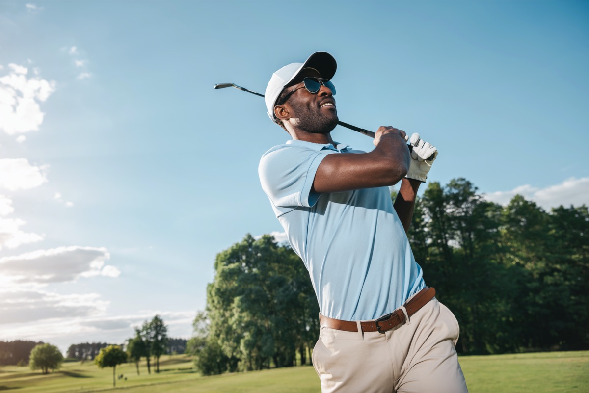 Smiling man man in cap and sunglasses playing golf health benefits of golf