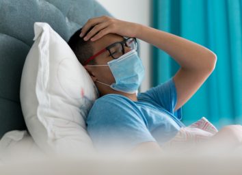 Teenage boy sick in bed with Covid-19 symptoms