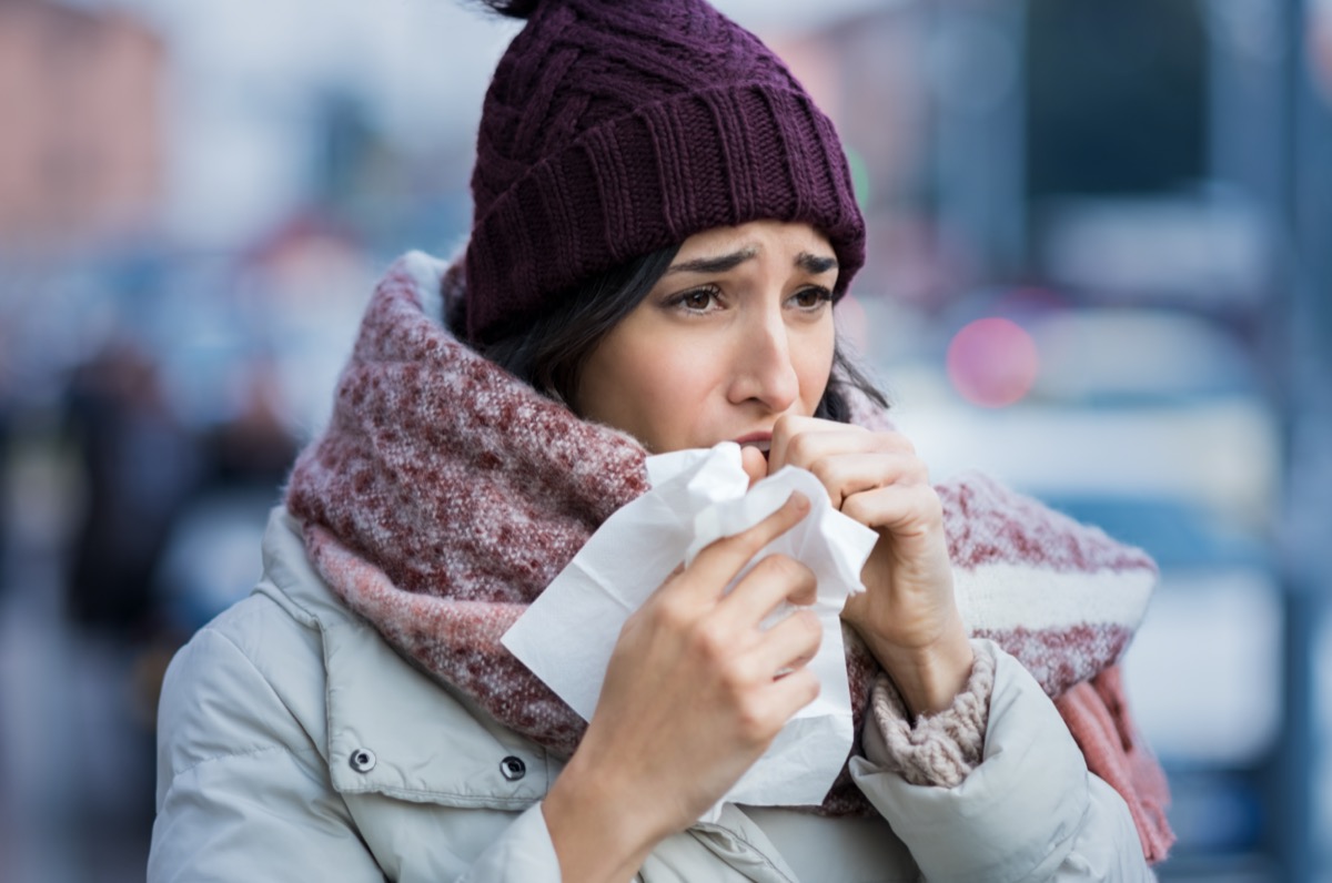 Young woman coughing during winter on street