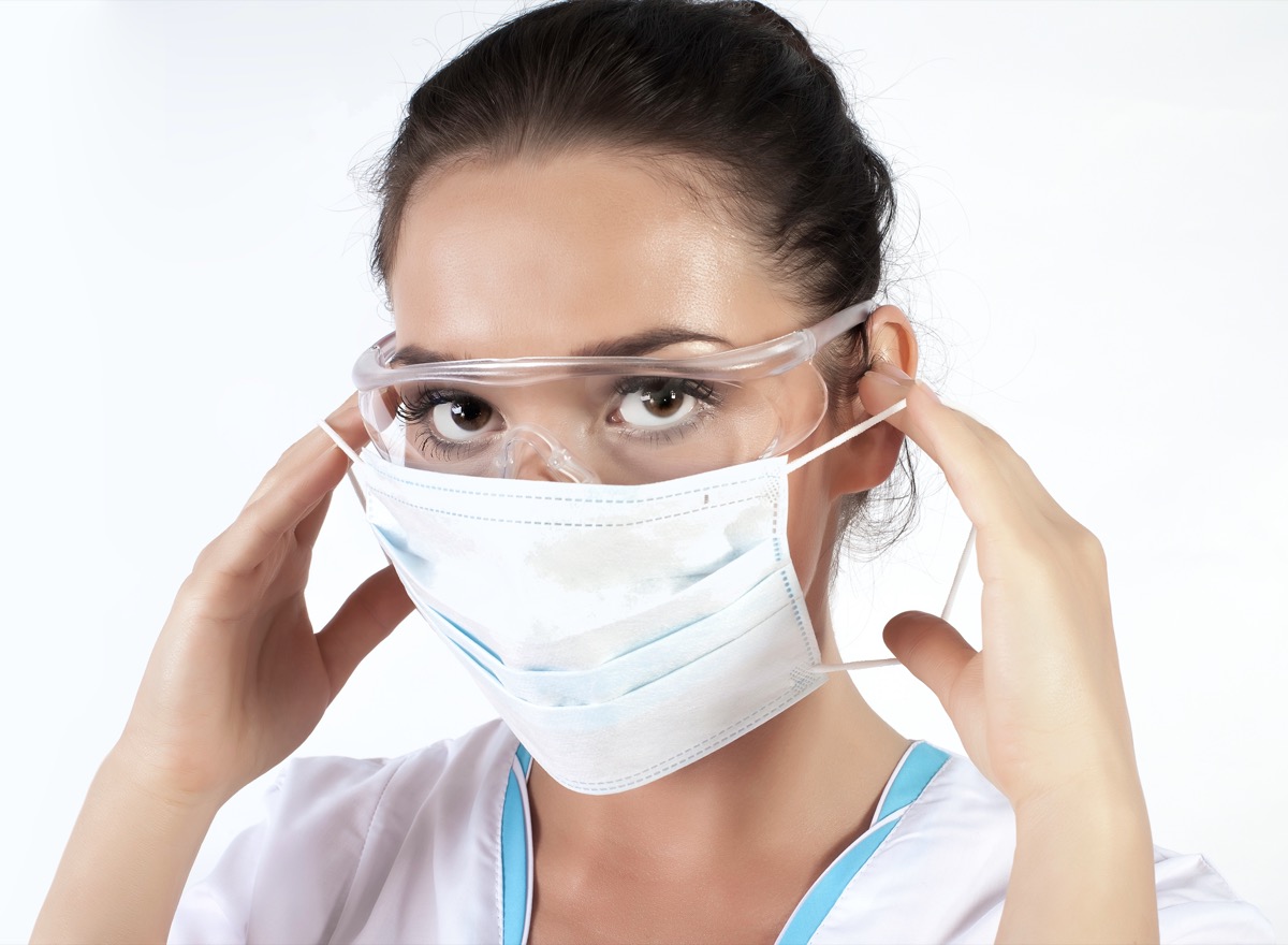 Female Medical Worker Wearing Protective Face Mask, goggles and Gear