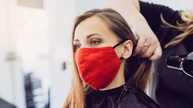 Woman wearing red face mask getting fresh styling at a hairdresser shop