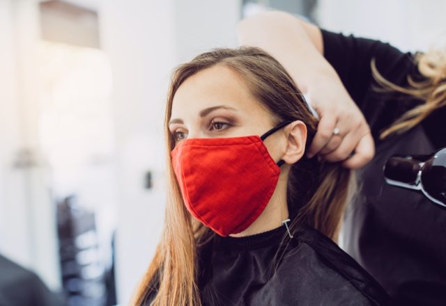 Woman wearing red face mask getting fresh styling at a hairdresser shop