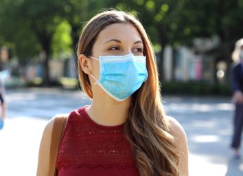 Social Distancing Woman in city street wearing surgical mask against disease virus SARS-CoV-2.