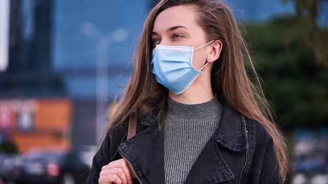 Woman wearing medical protective mask outdoors