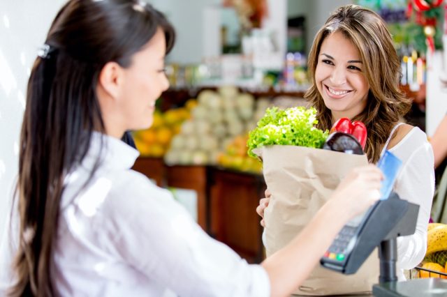 Woman at the local market's checkout paying by debit card