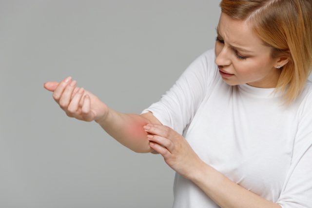 Woman removing band-aid from wound after injection of blood test
