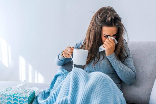 Sick woman with headache sitting under the blanket