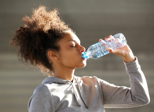 Schwarze Frau trinkt Mineralwasser