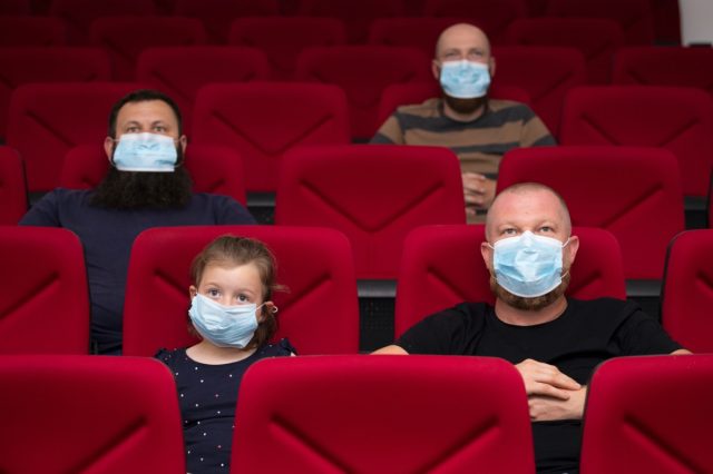 People in the cinema with protection mask keeping their distance to avoid physical contact