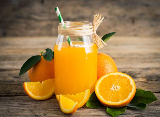 Glas frisch gepresster Orangensaft mit geschnittenen Orangenhälften